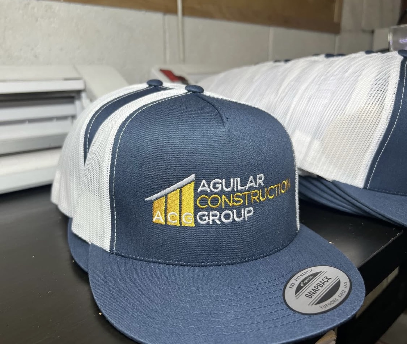 Navy and white trucker caps embroidered with a local construction company logo