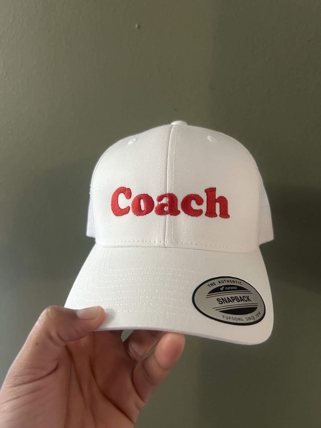 White snapback cap embroidered with the word Coach