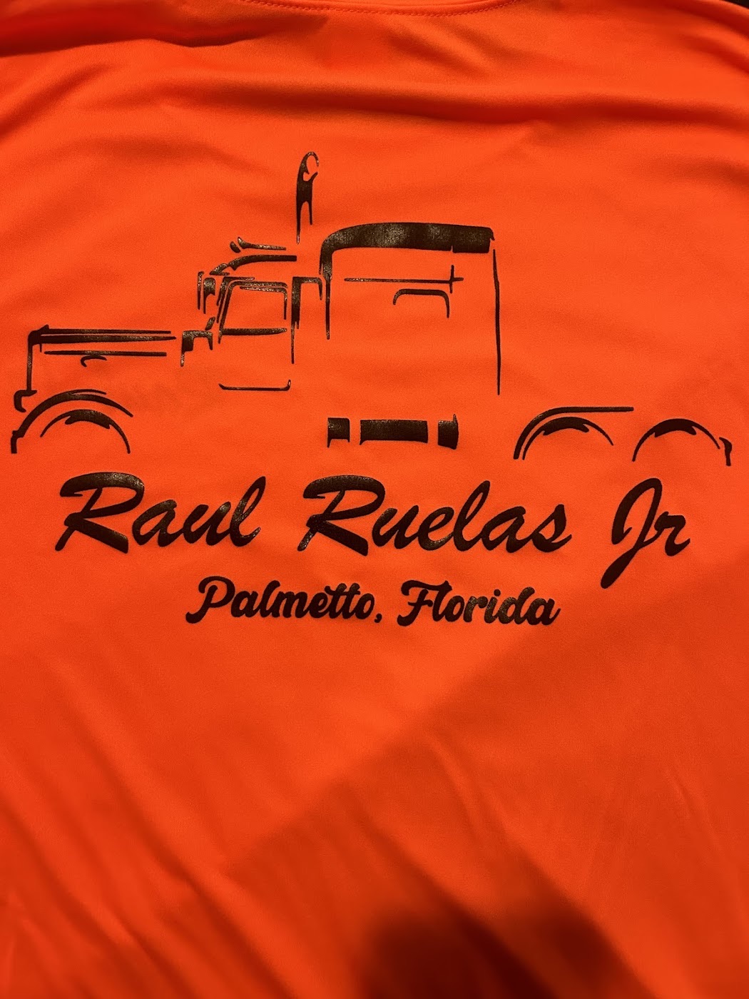Screen-printed orange dri-fit shirt with a black truck design